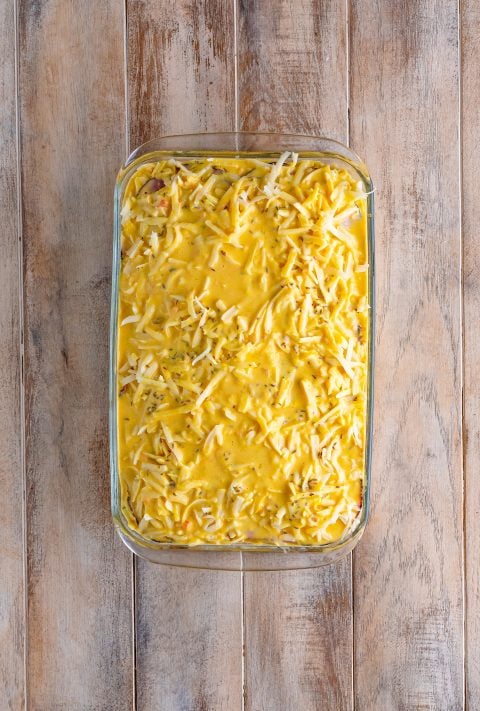 A milk, eggs, thousand island dressing and mustard mixture on top of a Reuben Casserole in a dish.