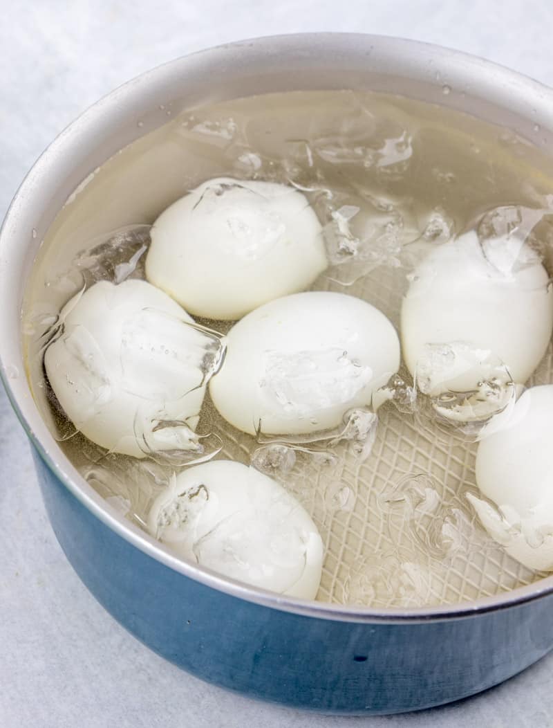 hard cooked eggs cooling in cold water and ice in a large sauce pan.