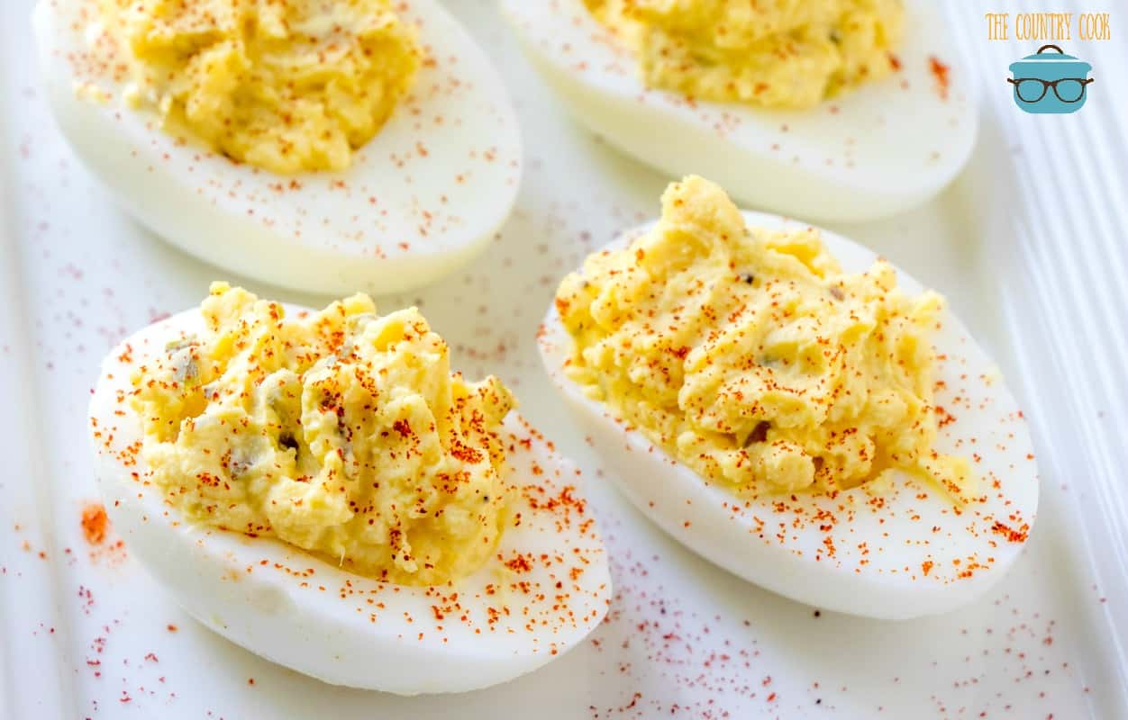 classic deviled eggs sprinkled with paprika on a white plate.