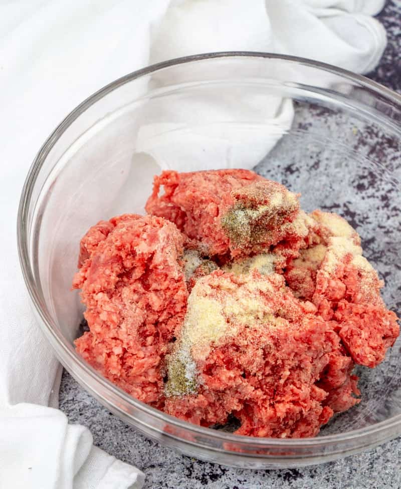 ground beef, onion powder, garlic powder, salt and pepper mixed together in a bowl.