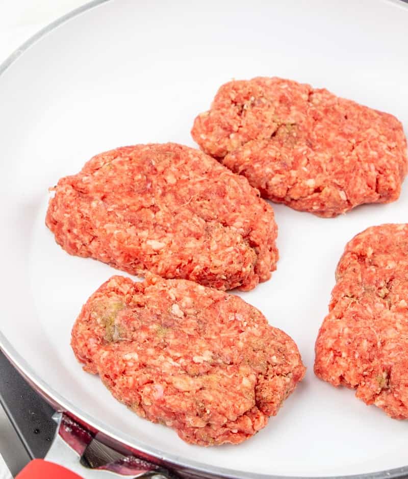 hamburger steaks cooking in a frying pan