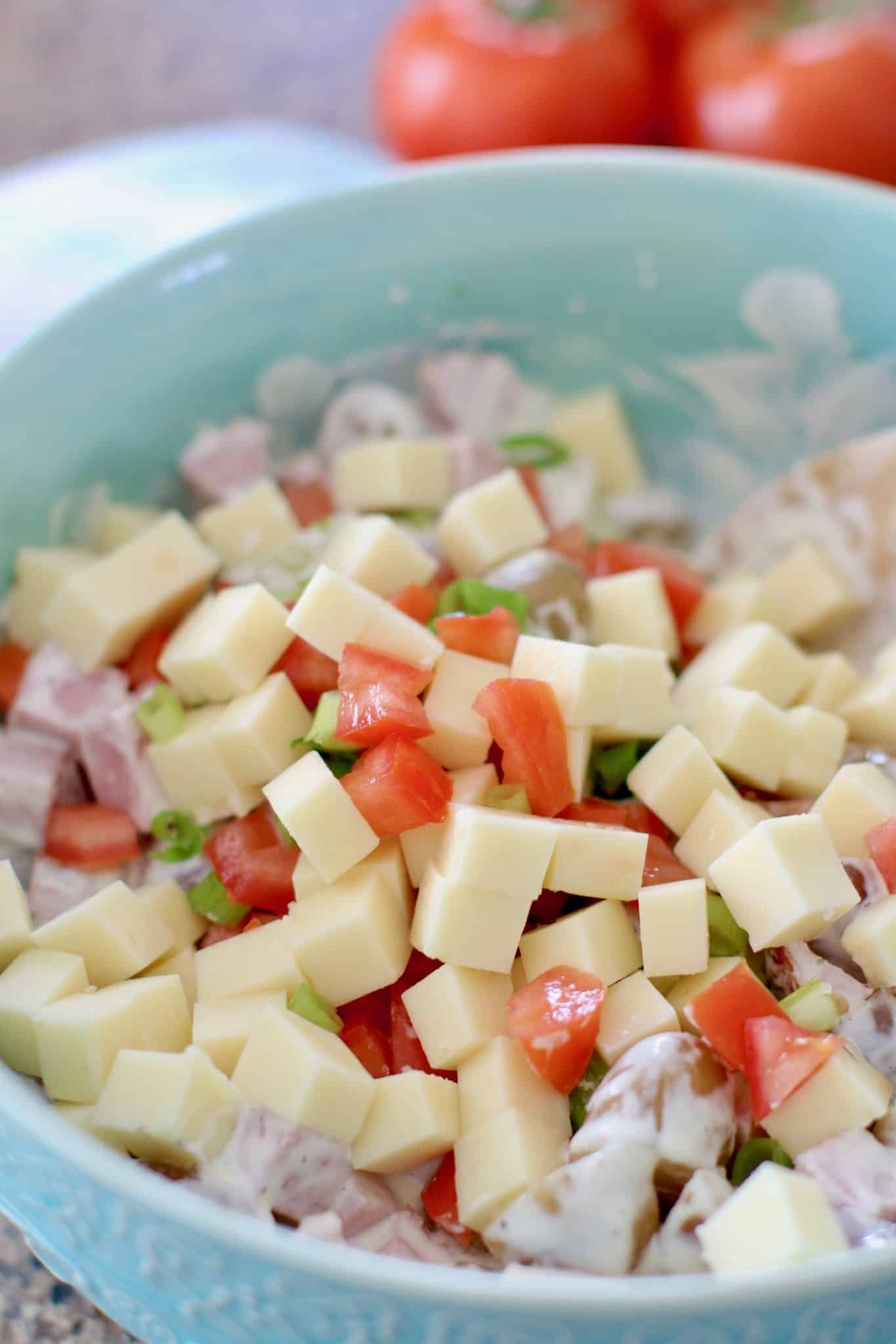cubed cheese and tomatoes added to bowl. 