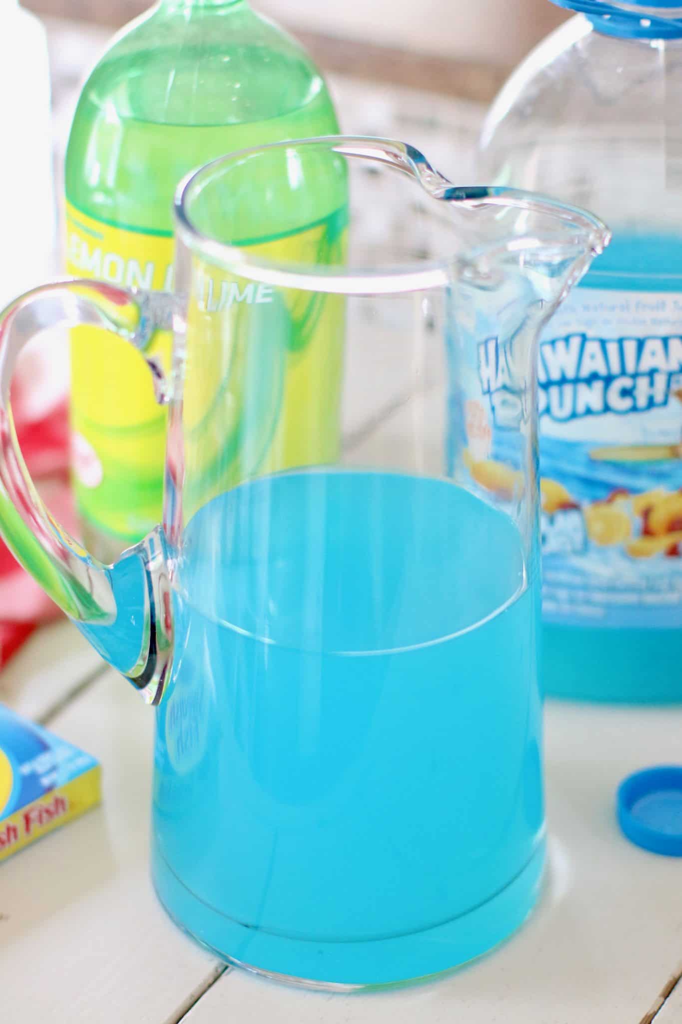 blue Hawaiian Punch punch poured into a large glass pitcher.