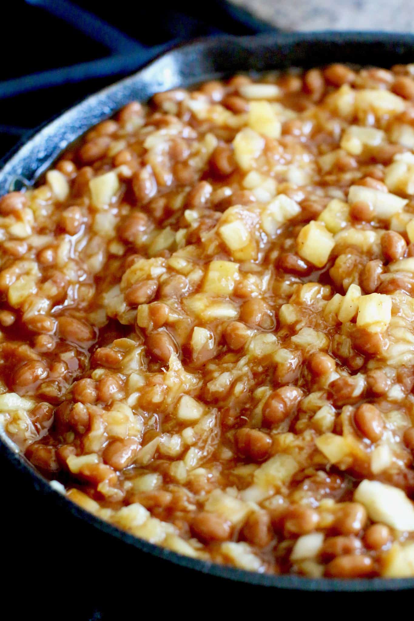 beans, pineapple and diced onions mixed together in a skillet.