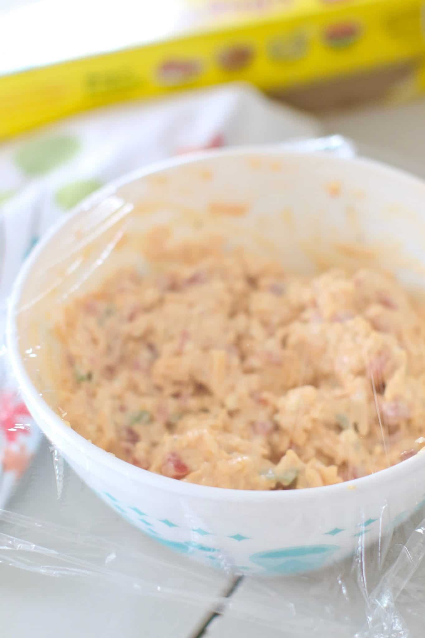 pimiento cheese spread in a bowl covered with plastic wrap.
