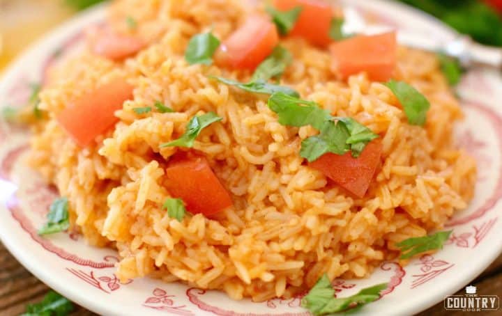 Mexican Rice shown on a plater and topped with diced tomatoes and chopped cilantro.