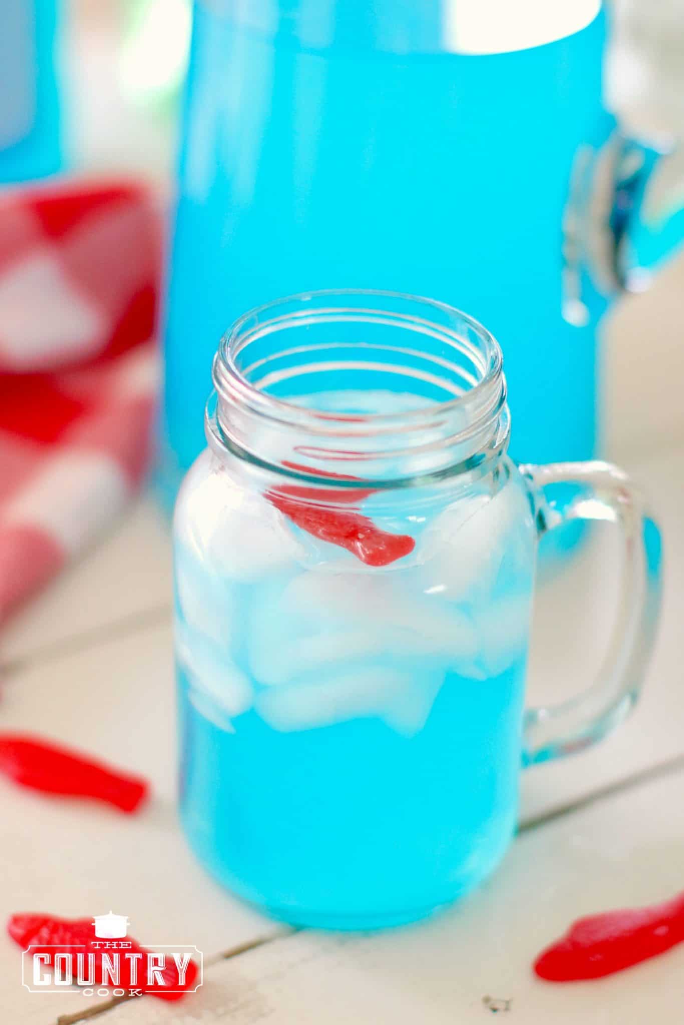glass of blue Ocean Water punch in a serving glass with a Swedish fish placed on top.