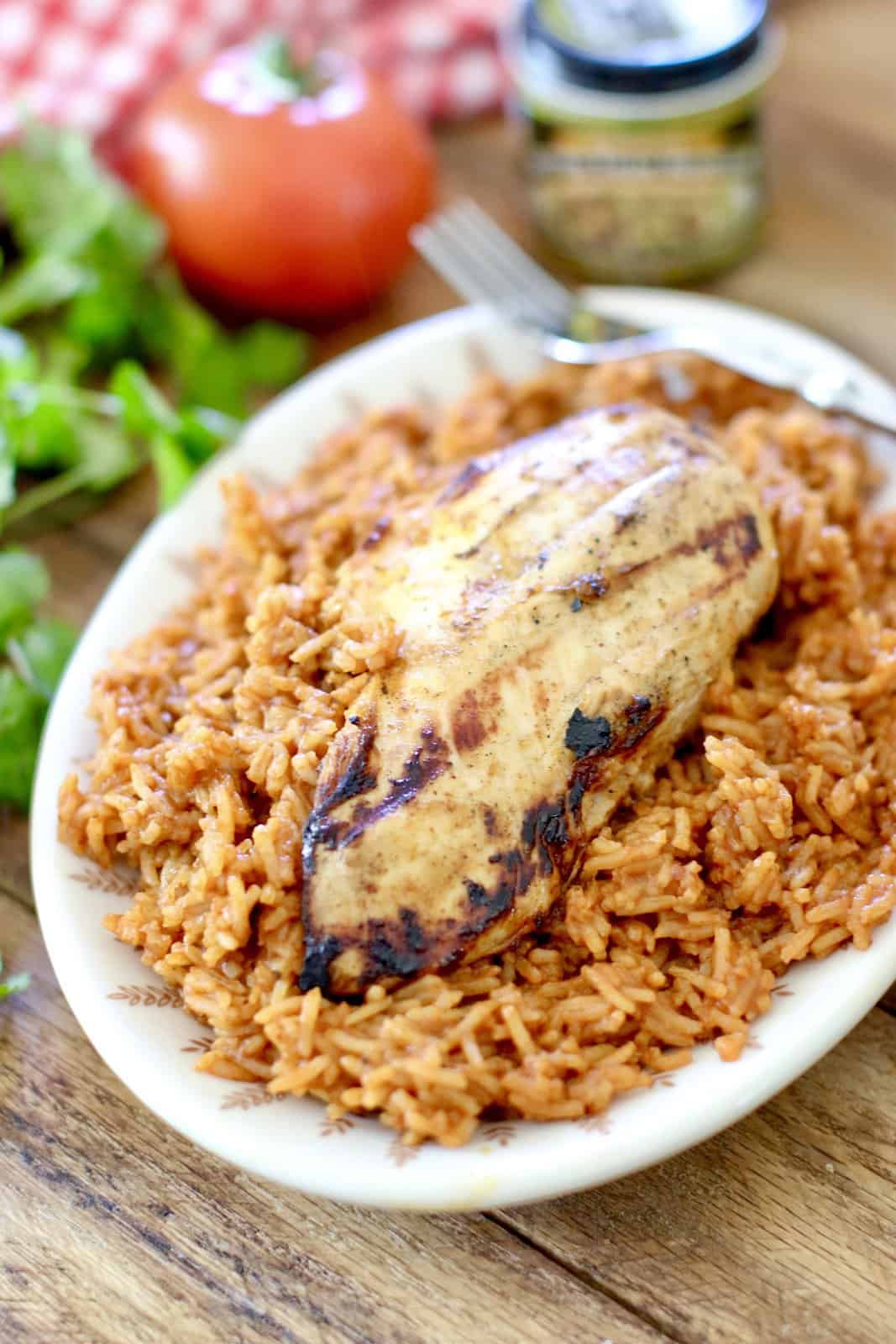 grilled lime chicken breast on Mexica rice on an oval plate. 