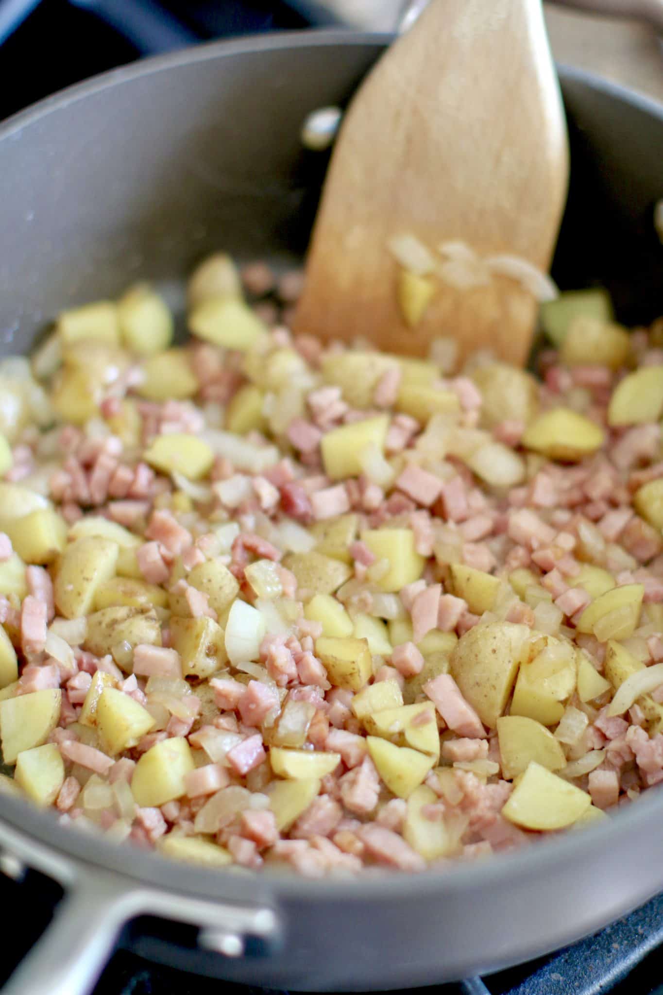 diced ham added to potatoes and onions in a skillet. 