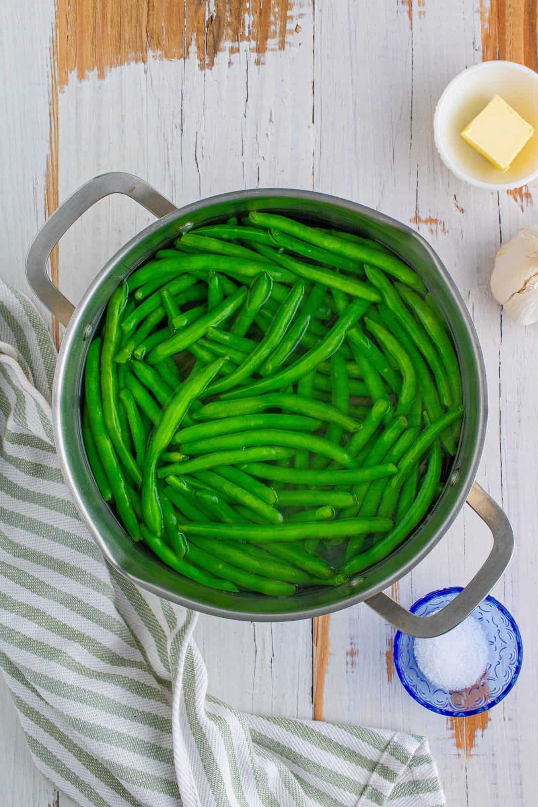 fresh green beans shown in a pot of water.