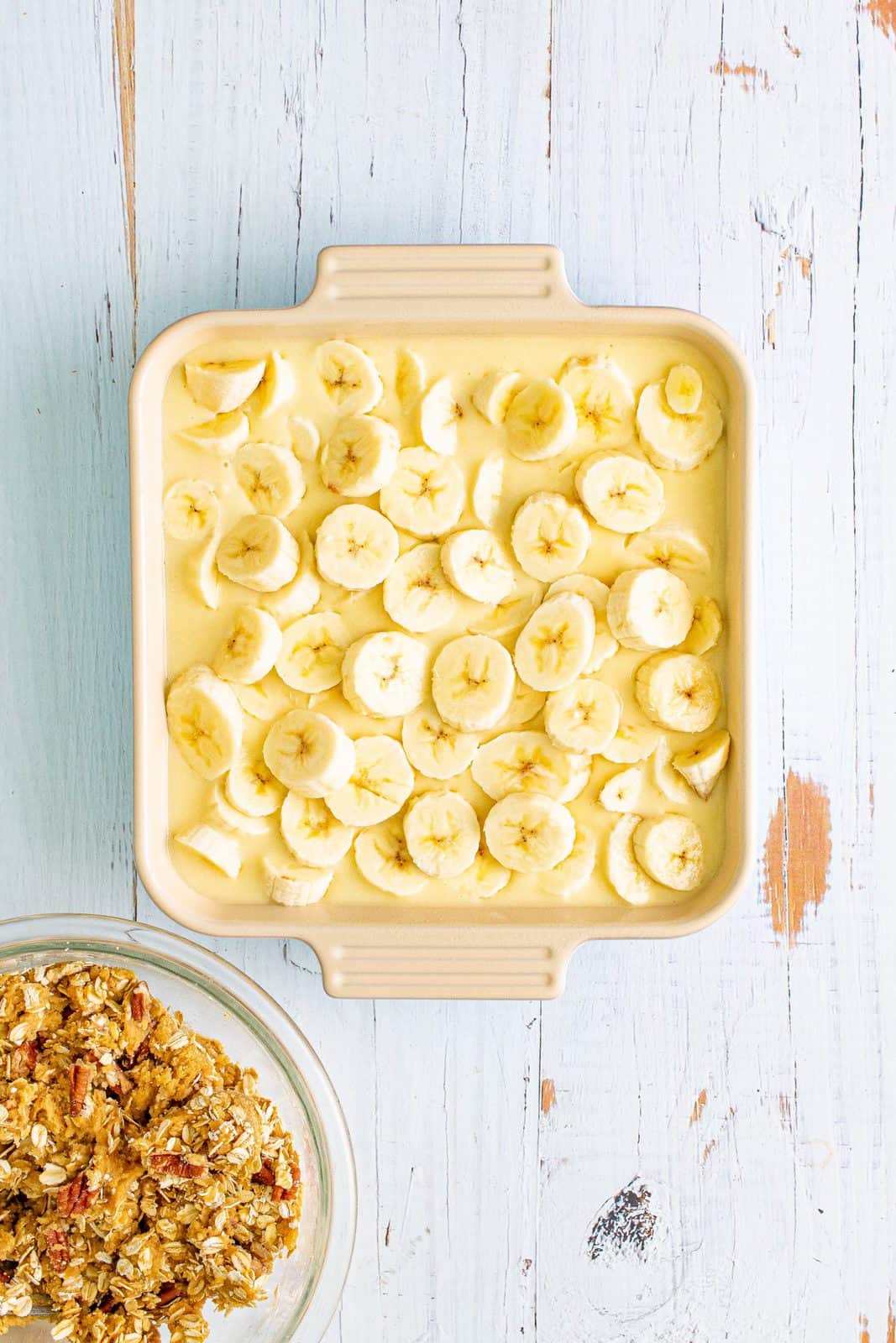 sliced bananas layered on top of batter in a square pan