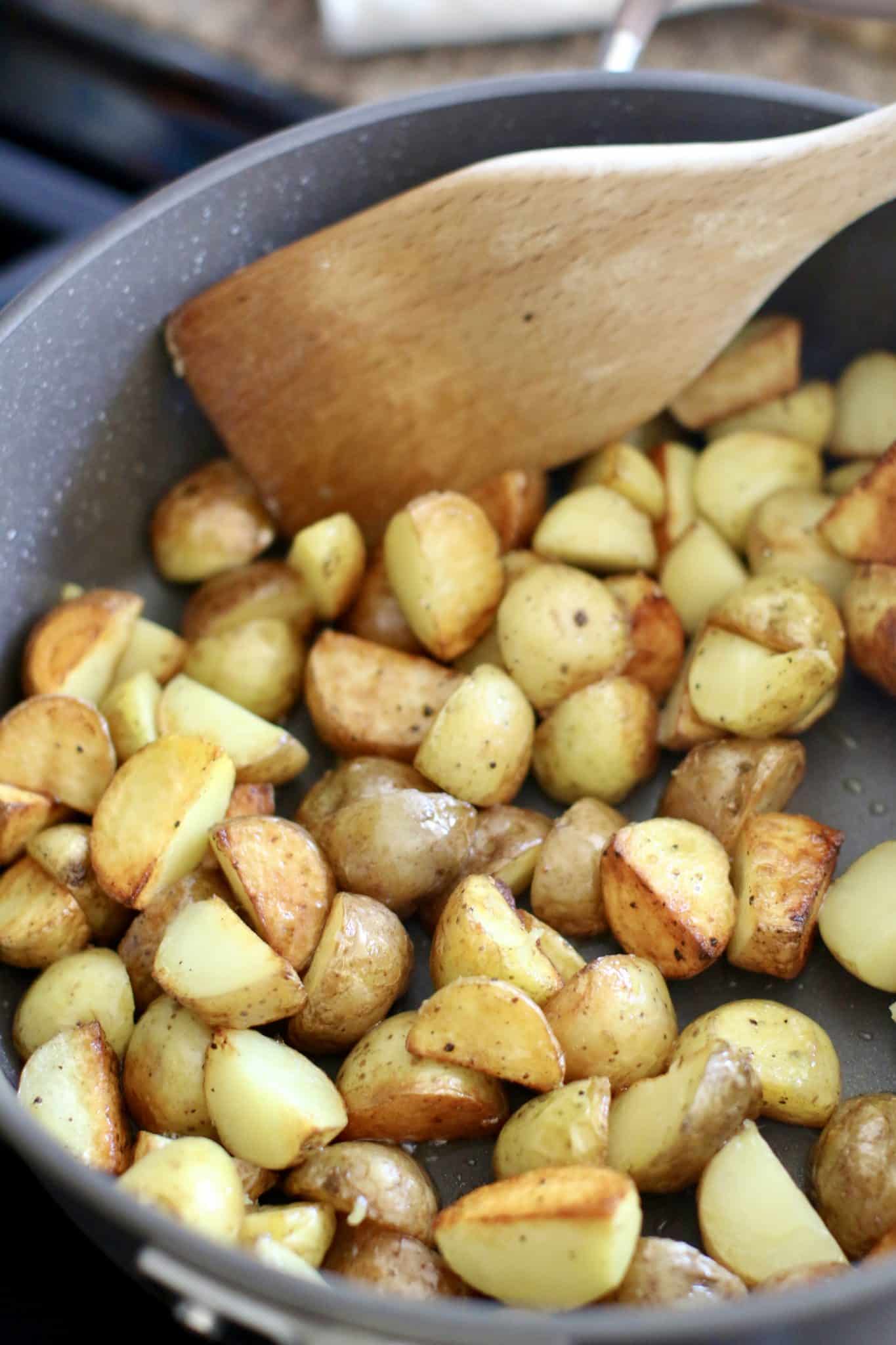 cut potatoes being fried in a skillet. 