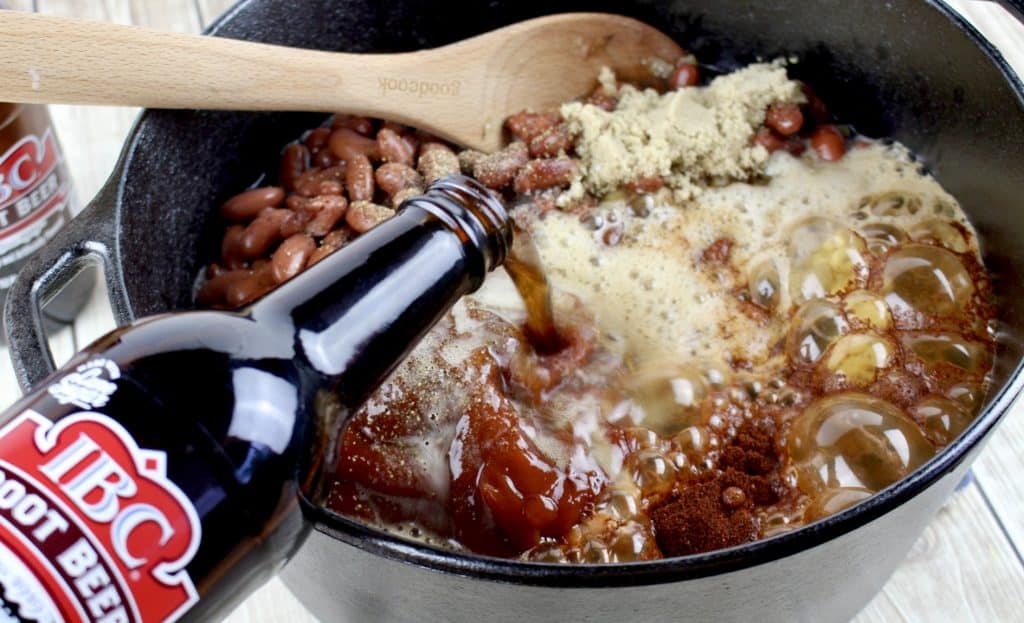 root beer being added to pot of beans
