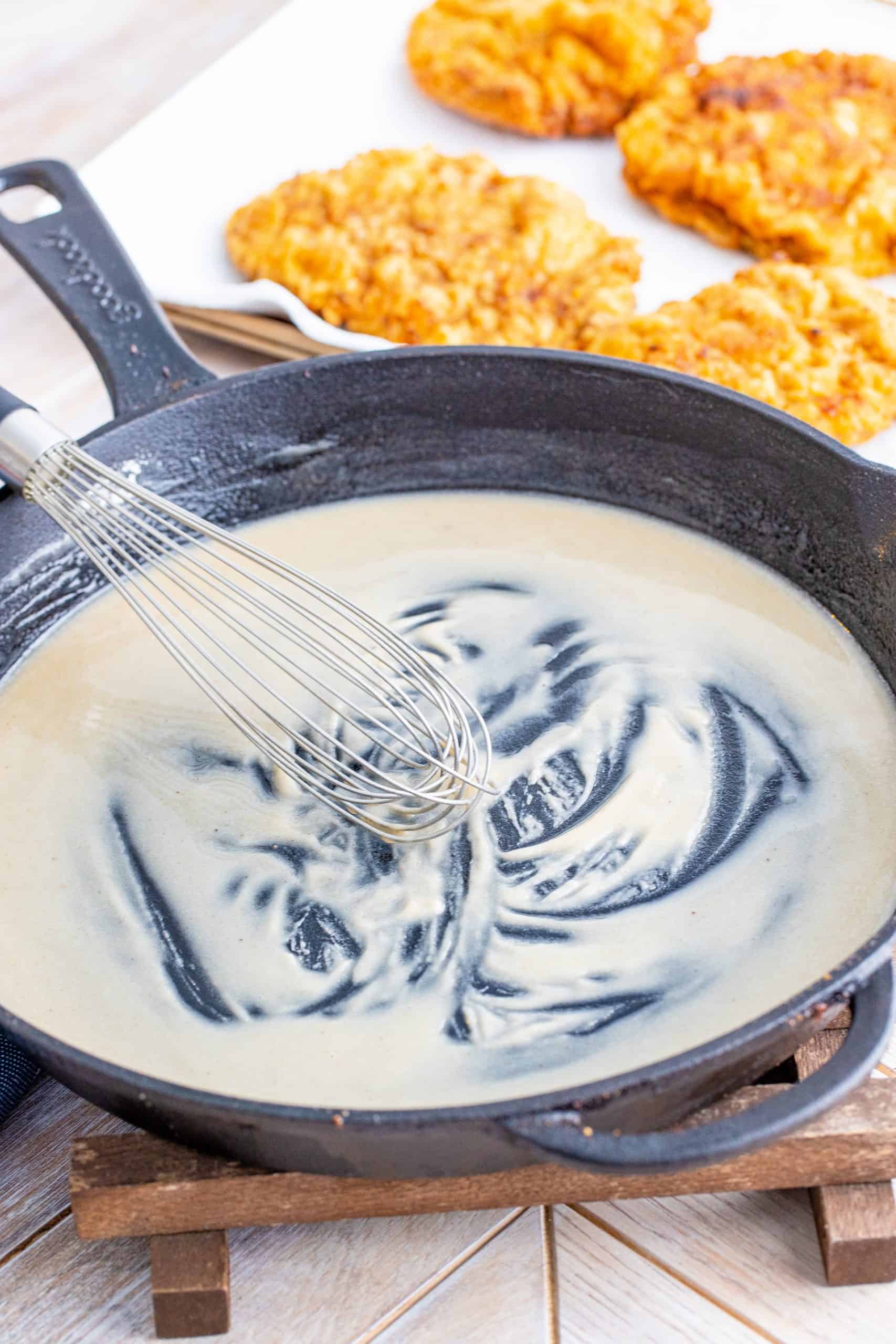 whisking flour and oil together in a cast iron pan.