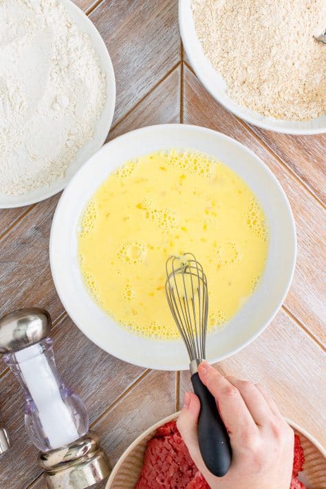 eggs and milk whisked together in a white bowl