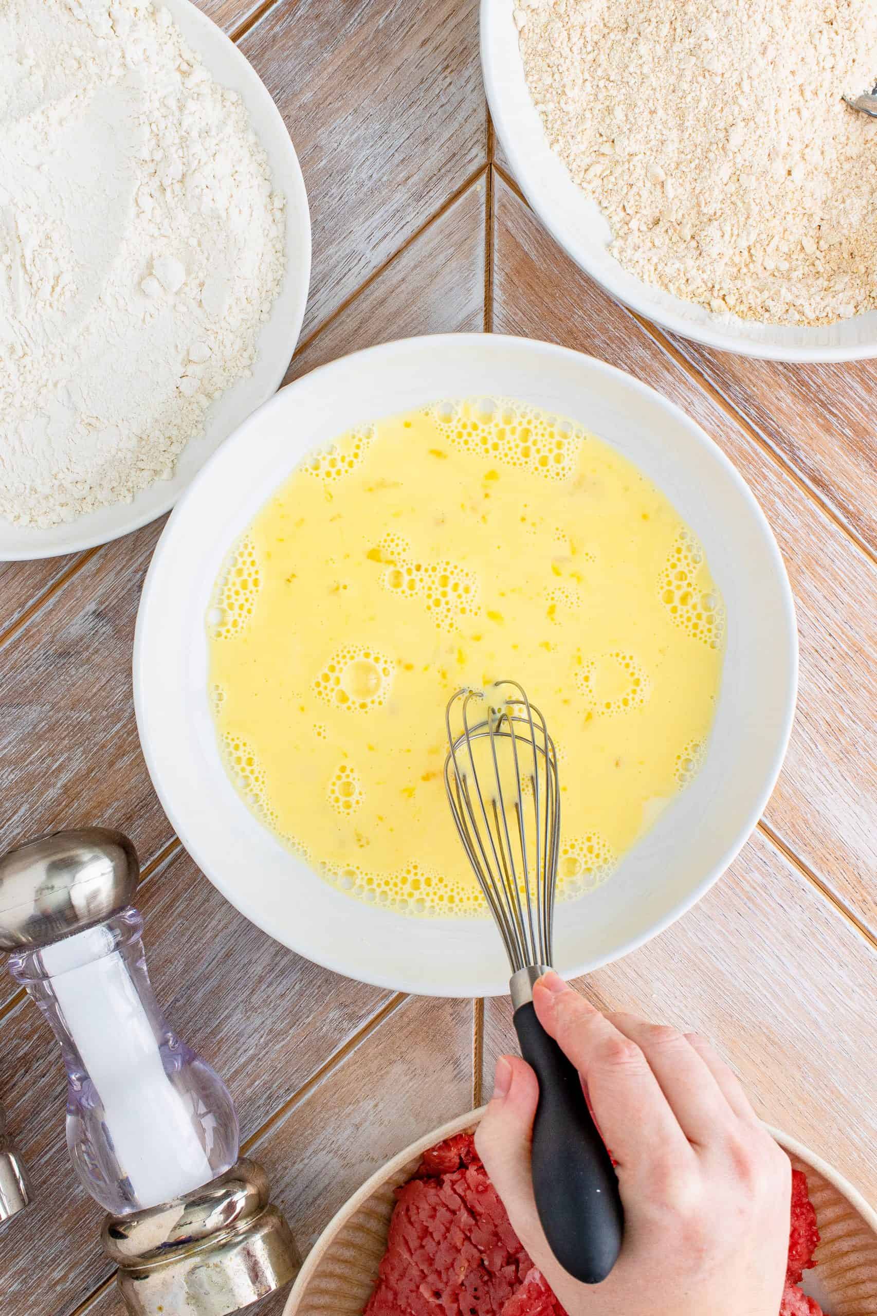 eggs and milk whisked together in a white bowl.