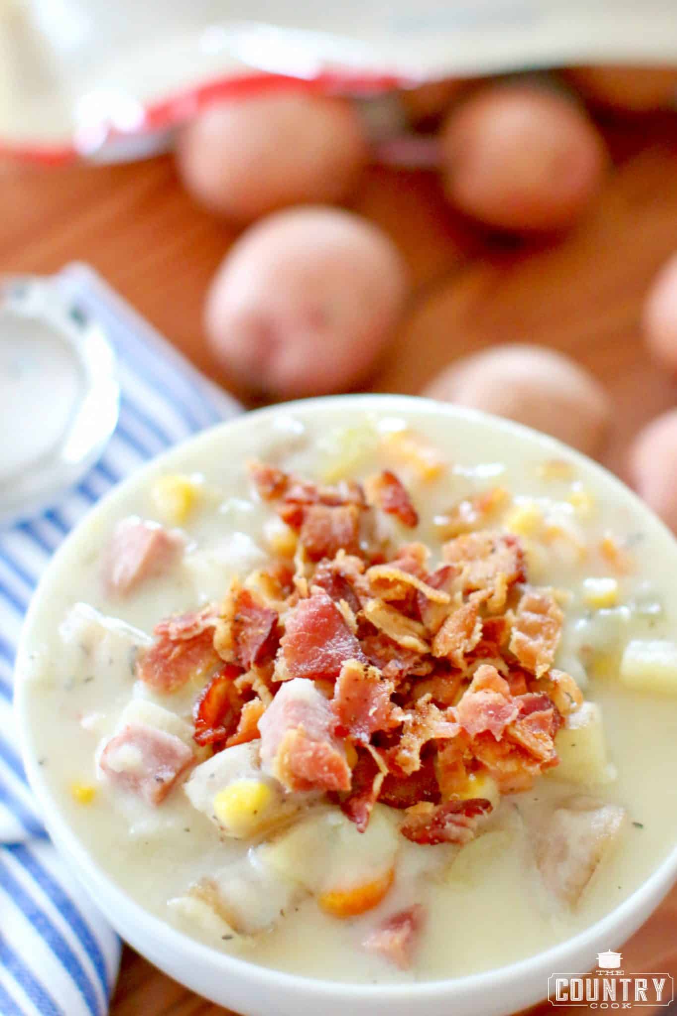 Crumbled bacon on ham, potato and corn chowder in a bowl.