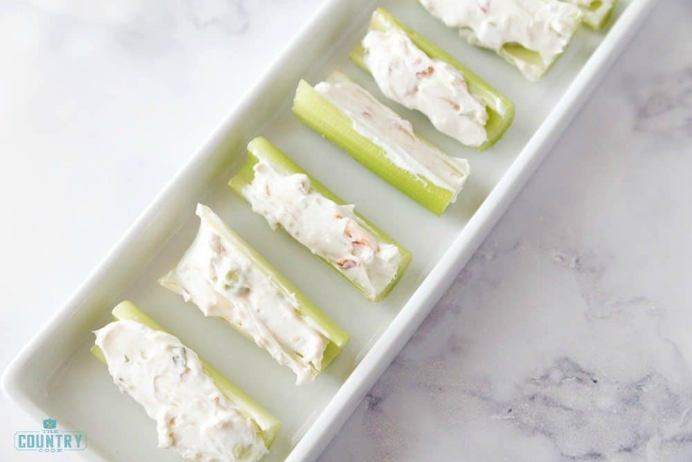 celery pieces stuffed with cream cheese mixture on a white platter. 