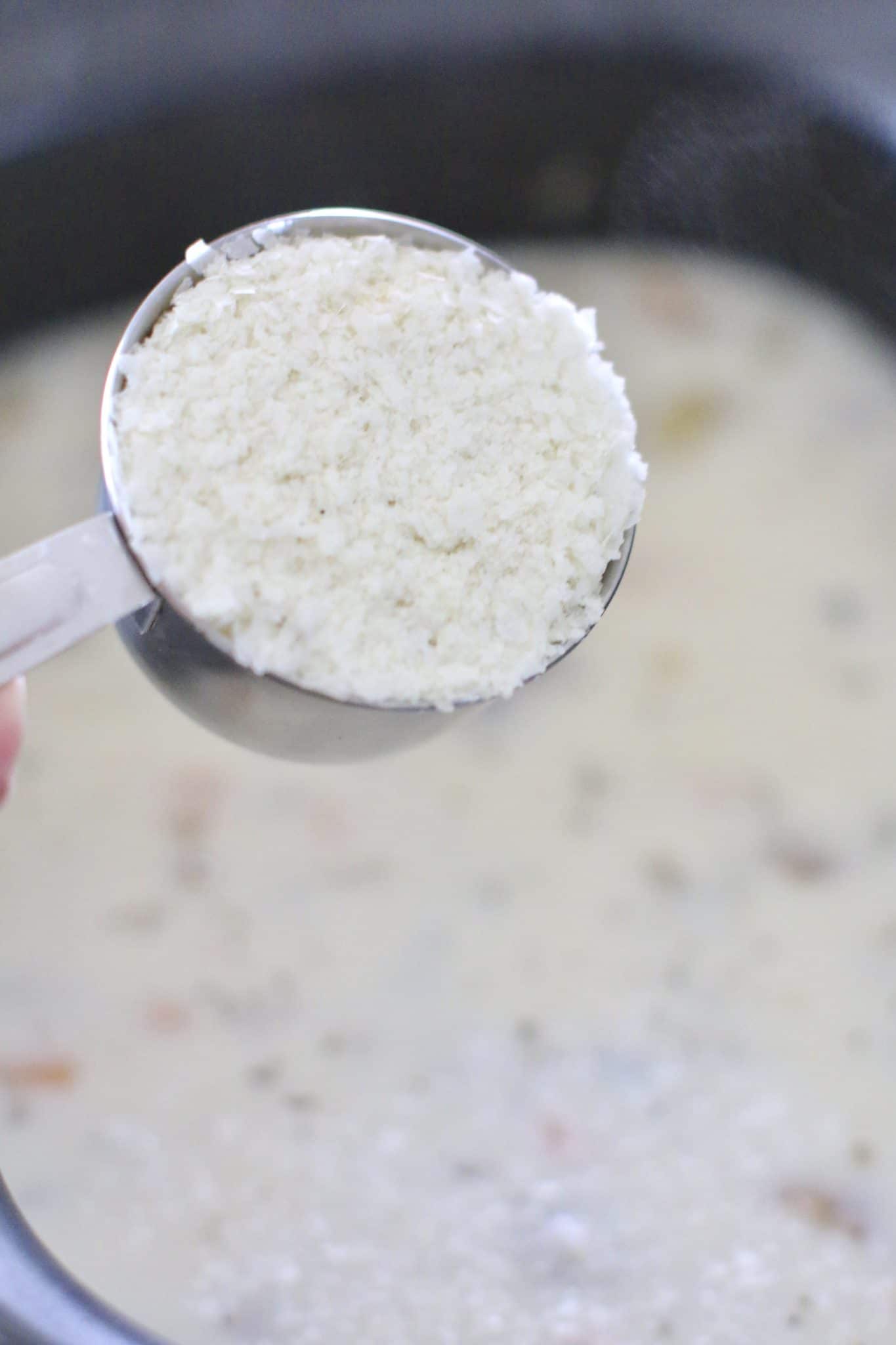 instant mashed potato flakes being poured into a crock pot chowder.