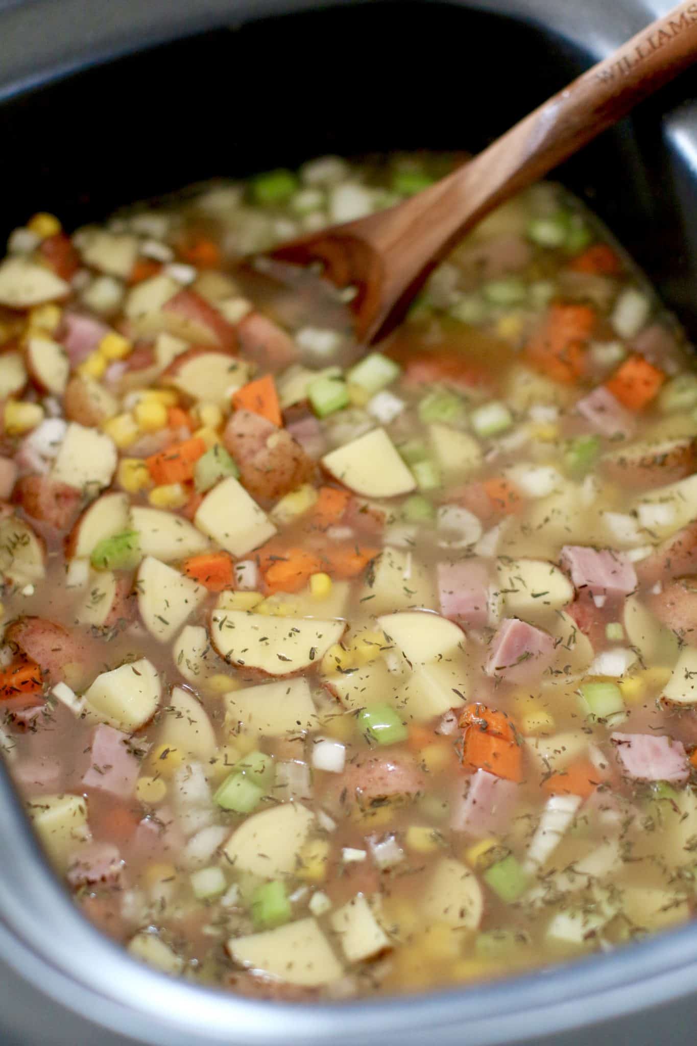 slow cooker filled with chicken broth, diced potatoes, ham, carrots, celery and seasoning.