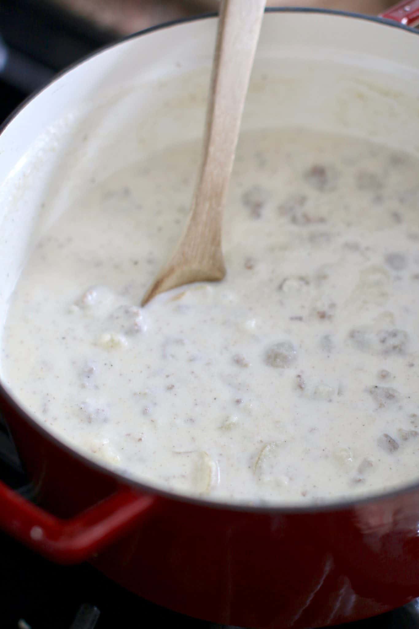 creamy hamburger soup being stirred with a spoon.