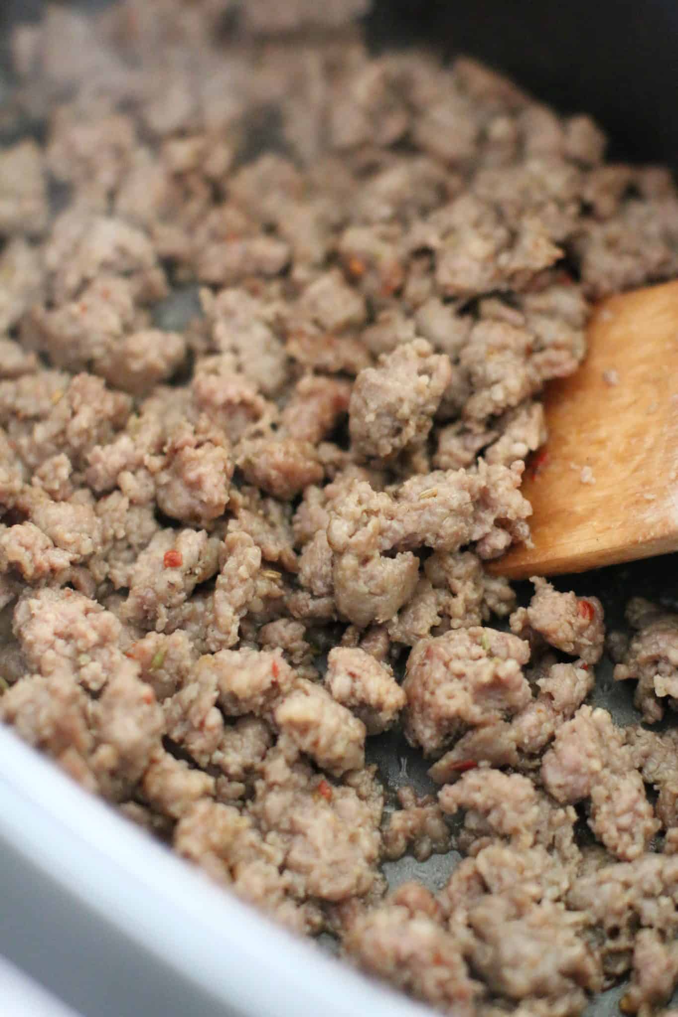 ground beef in slow cooker with wooden spoon.
