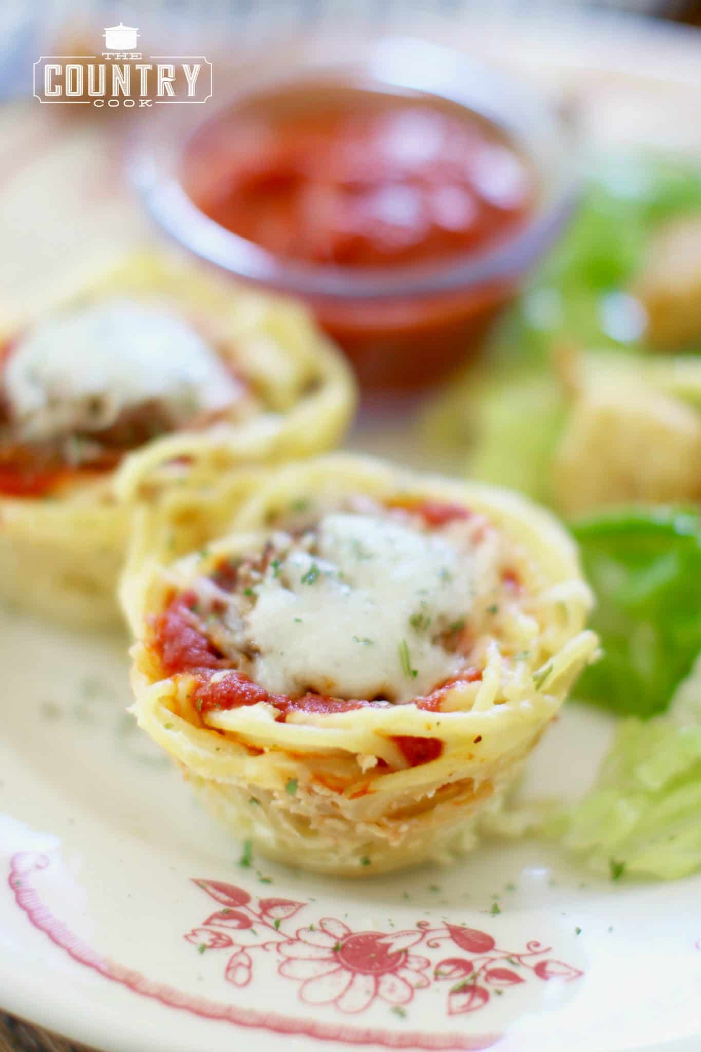 fully cooked spaghetti nests on a plate served with a salad and marinara sauce, sprinkled with parsley flakes