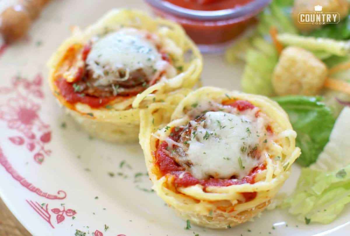 kid-friendly spaghetti cups with sausage served on a plate with spaghetti sauce and a salad