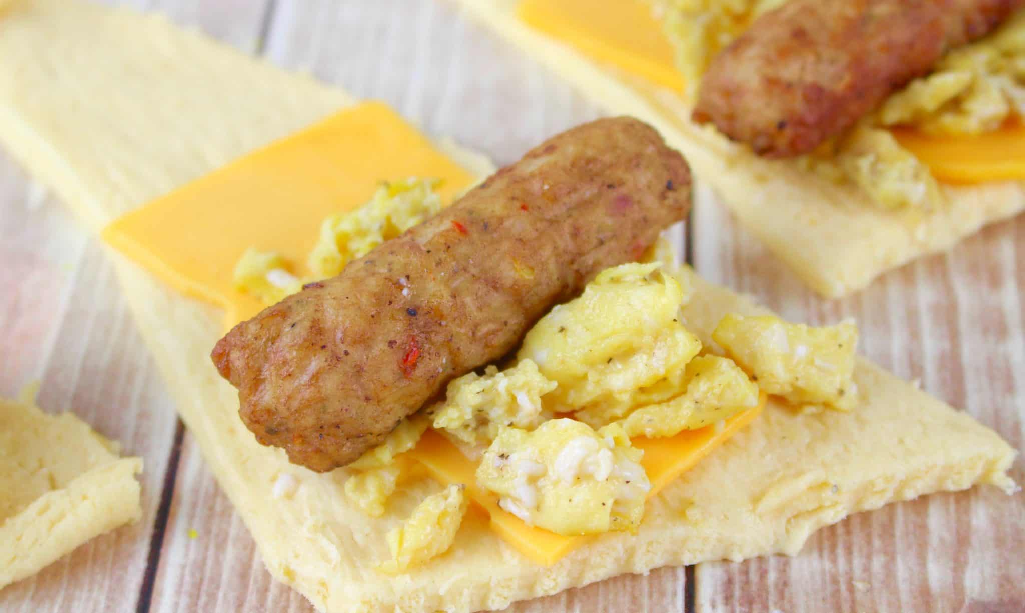 crescent roll, cheese, scrambled eggs and sausage link on a piece of crescent roll.
