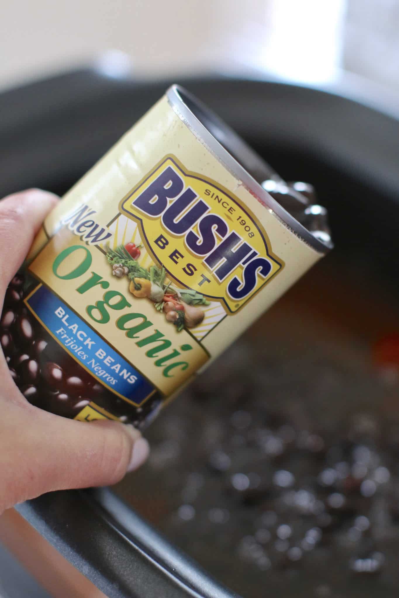 pouring BUSH'S Organic Black Beans into a slow cooker.
