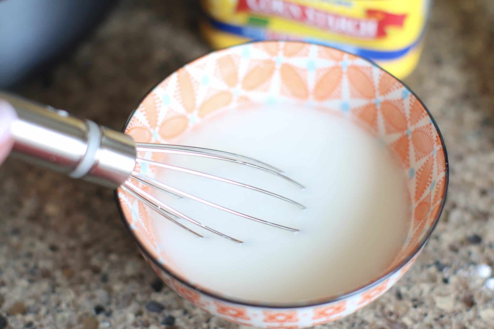 corn starch slurry in a bowl with a small whisk.