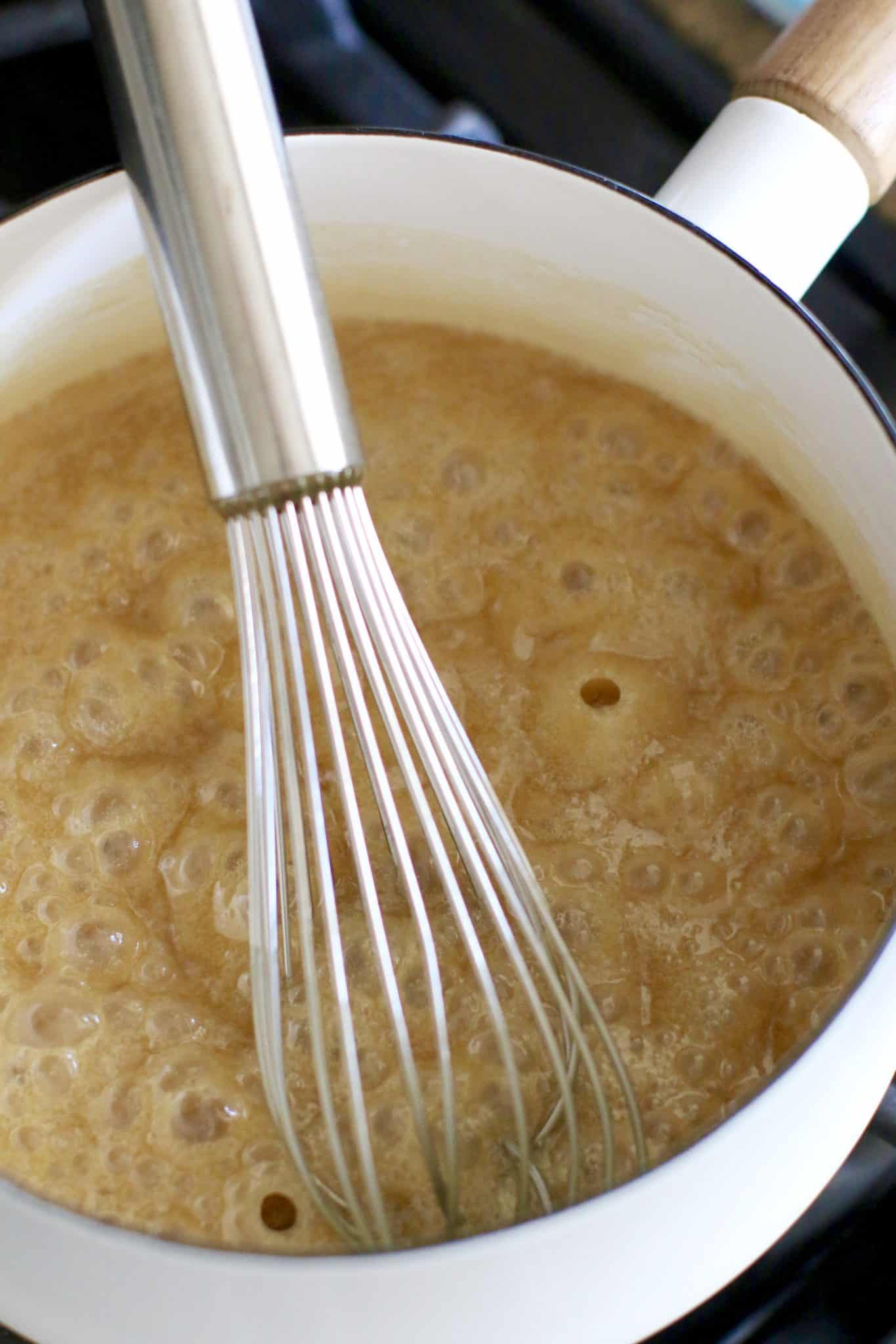 caramel glaze shown in a white pot and a whisk. 