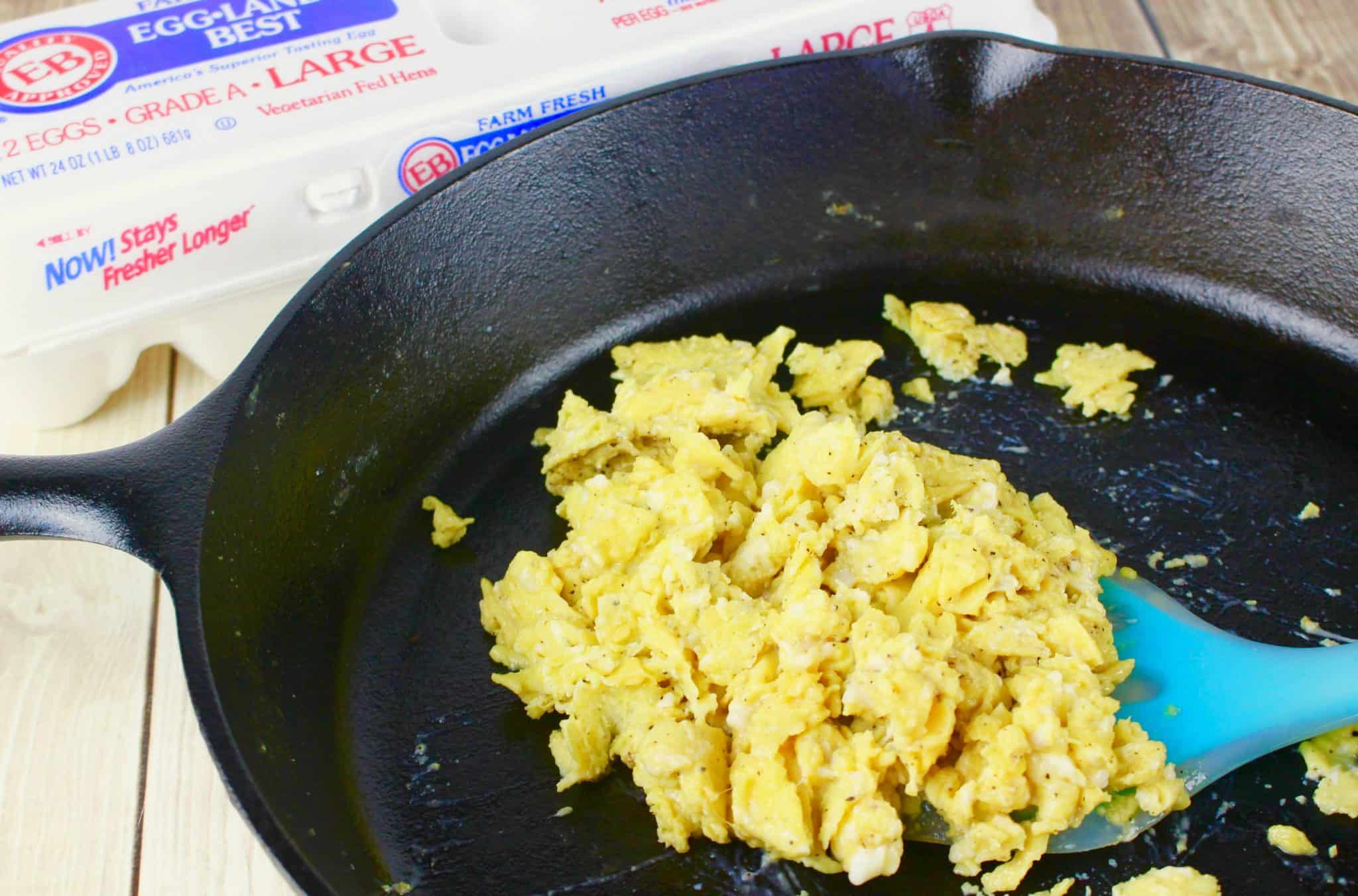 eggs being scrambled in a cast iron skillet. 