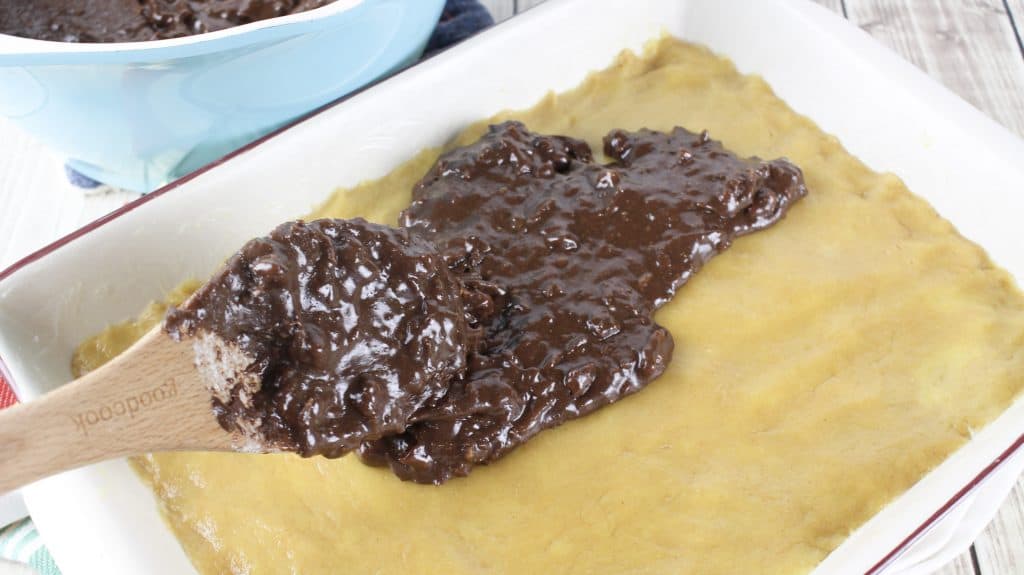 fudge filling spread onto peanut butter cake mix in a pan