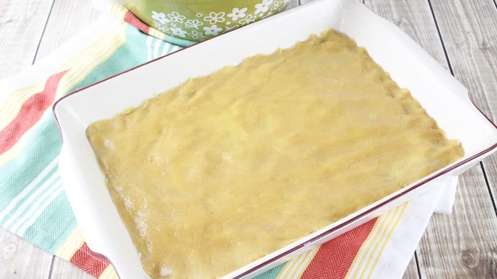 peanut butter cake mix batter spread into the bottom of a rectangular baking dish