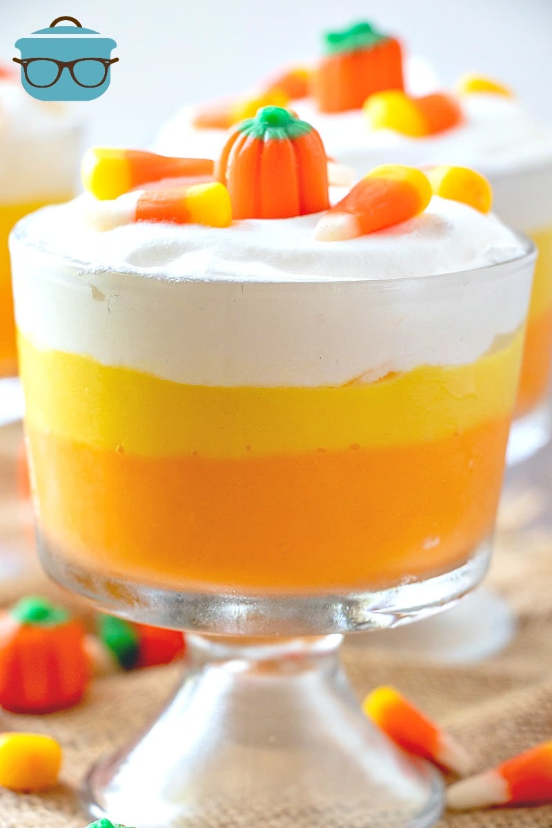 Candy Corn colored layered pudding in glass dessert cups topped with candy corn and mallow creme pumpkins.