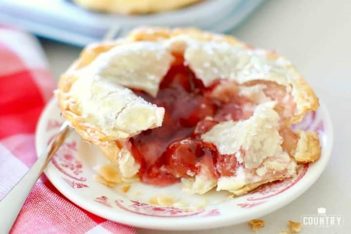 Mini Cherry Cheesecake Pie shown on a small pink and cream plate with a fork.