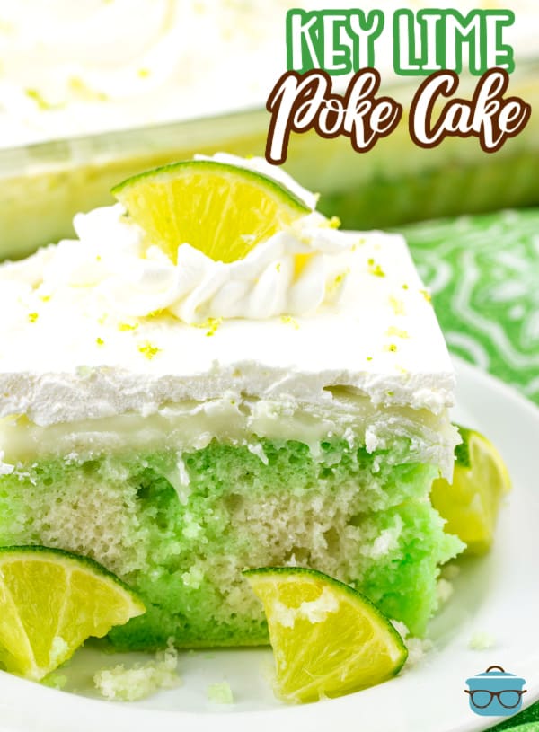 a slice of Key Lime Poke cake shown on a small round white plate with small lime wedges. 