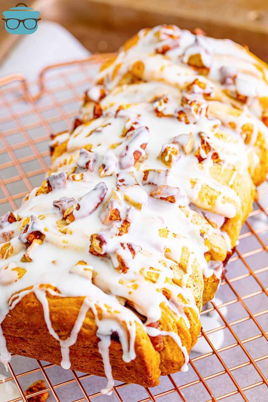 icing drizzled on top of cinnamon apple pull apart bread on a cookie rack. 