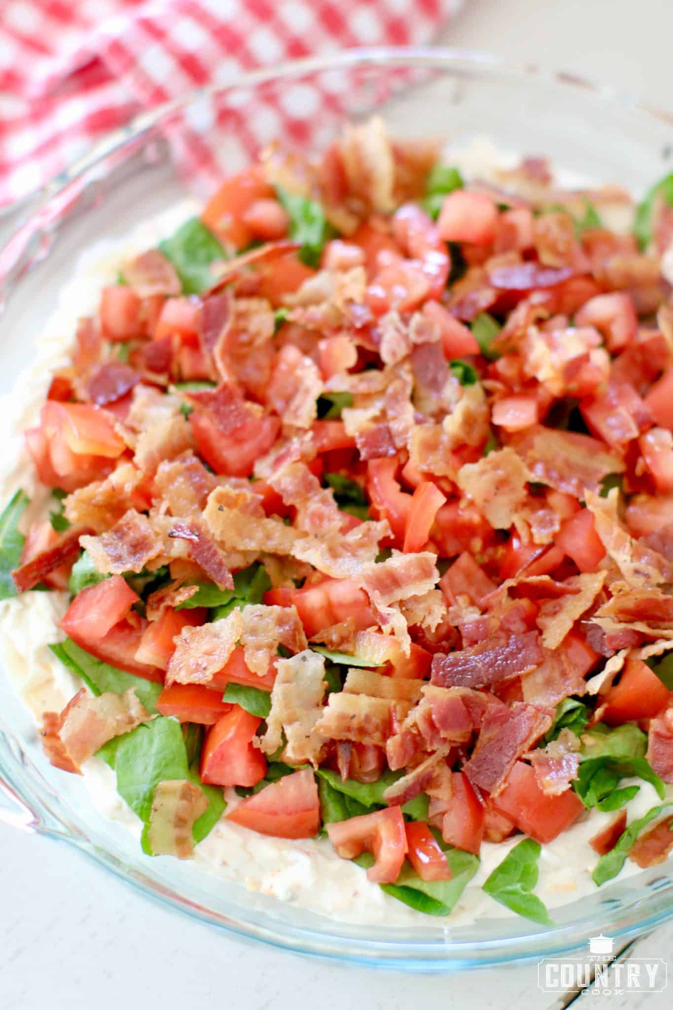 Lettuce, Tomatoes and Bacon on Veggie Cream Cheese Dip in a clear pie dish.