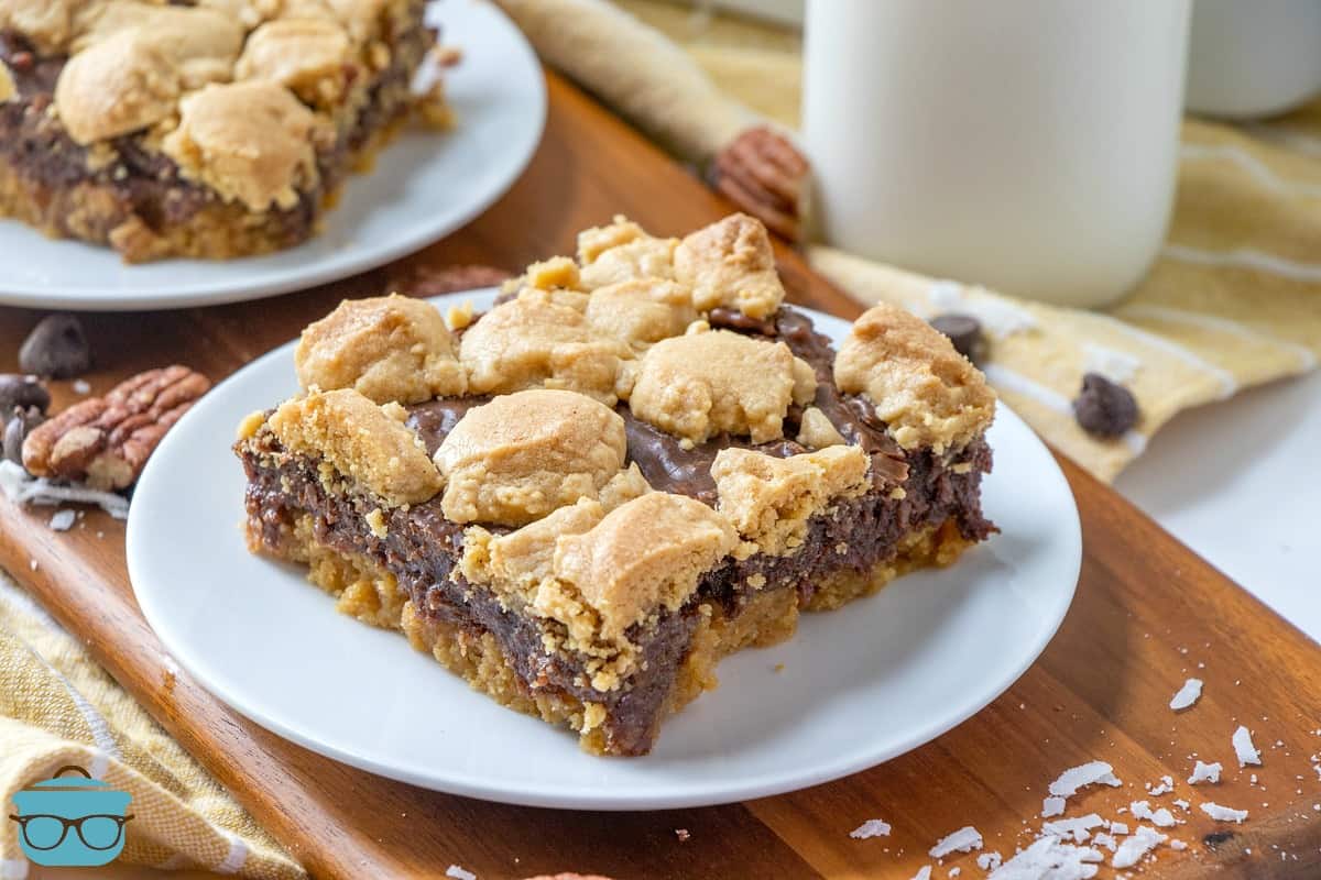 Fudge-filled peanut bars, slice on a white plate with a jar of milk in the background.