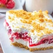slice, No Bake Cherry Yum Yum layered dessert recipe on a plate with milk pictured in the background
