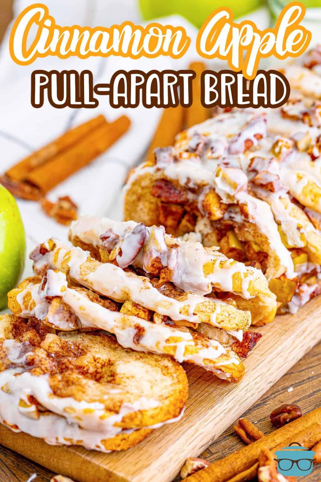 side photo of cinnamon apple pull apart bread on a wooden board with cinnamon sticks in the background. 