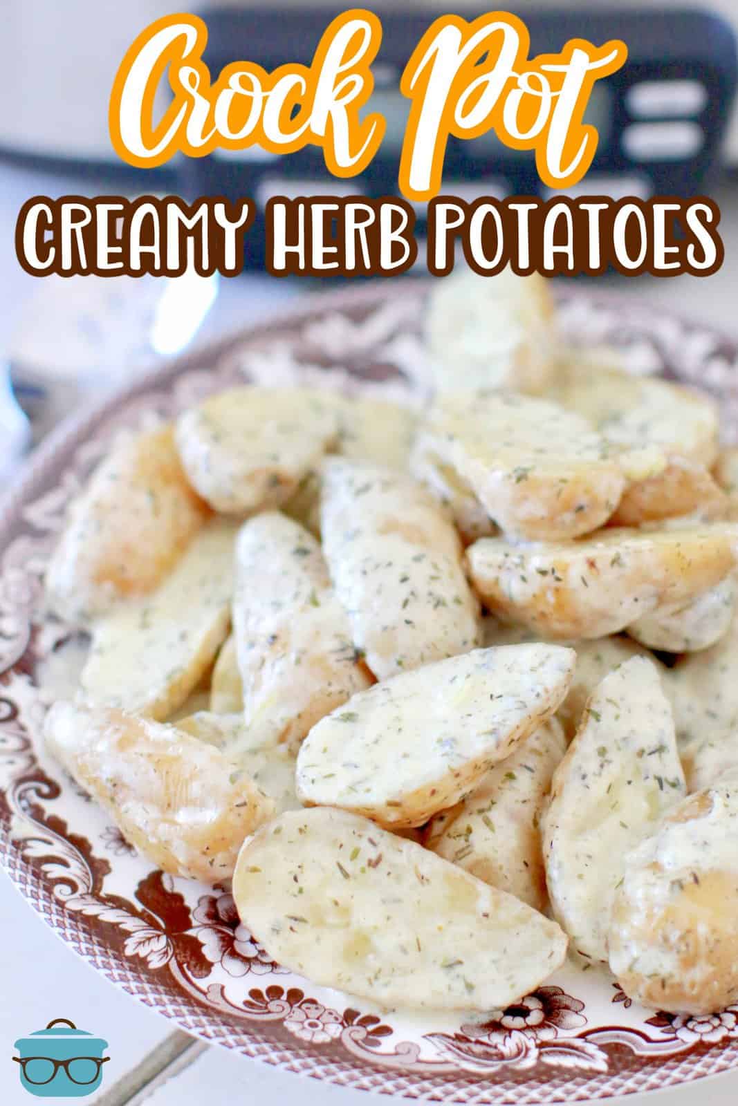 fully cooked sliced fingerling potatoes in a creamy herb sauce shown on a brown and white plate with a slow cooker in the background. 