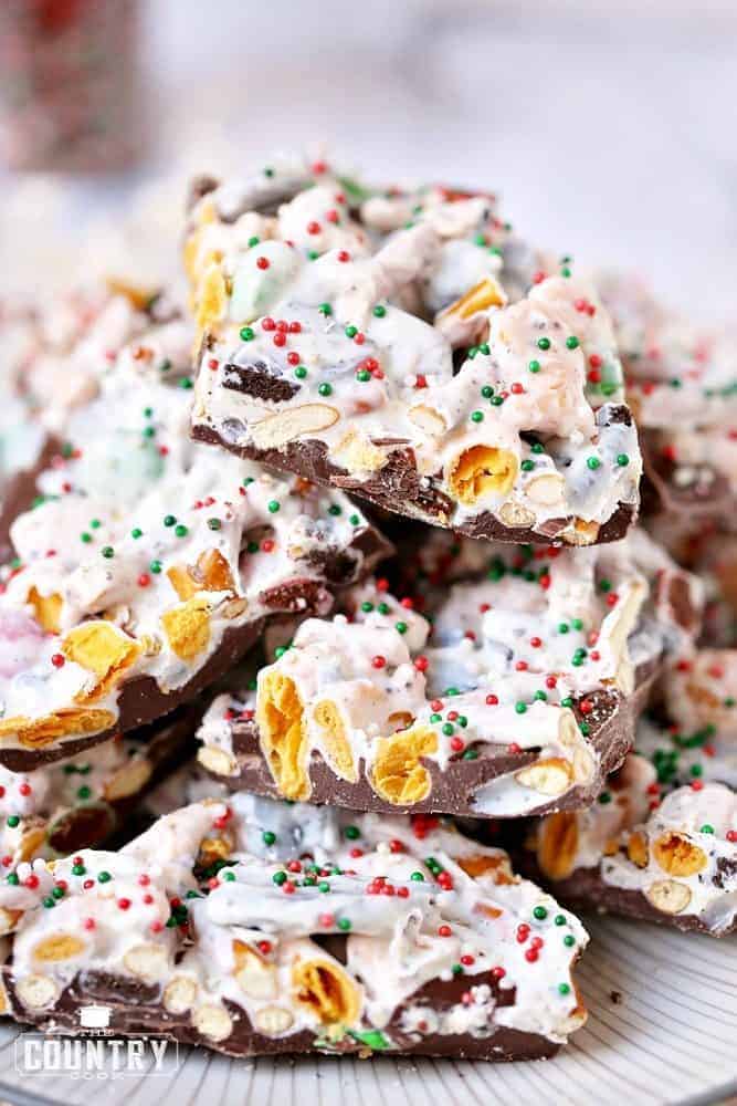 Candy Bark shown broken up into pieces and stacked together on a white plate. 