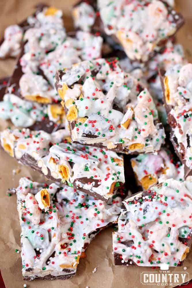 broken up pieces of candy bark shown stacked on brown parchment paper. 