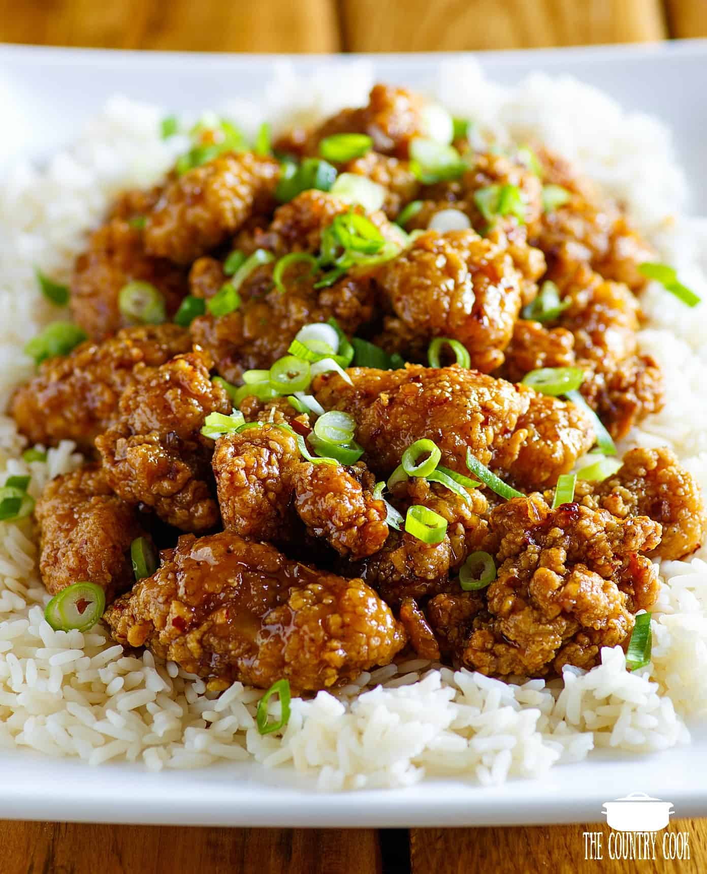 Easy Honey Garlic Chicken made with popcorn chicken shown on a bed of white rice on a white platter.