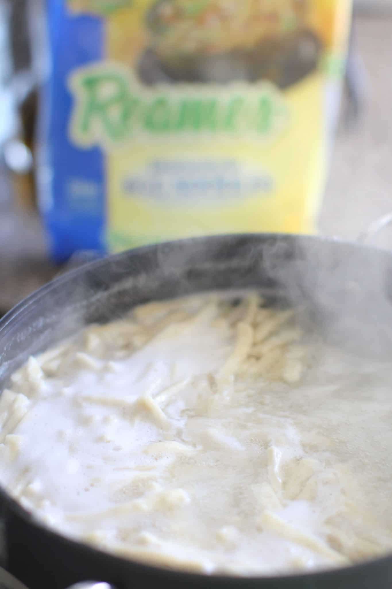 egg noodles shown boiling in water in a large pot.