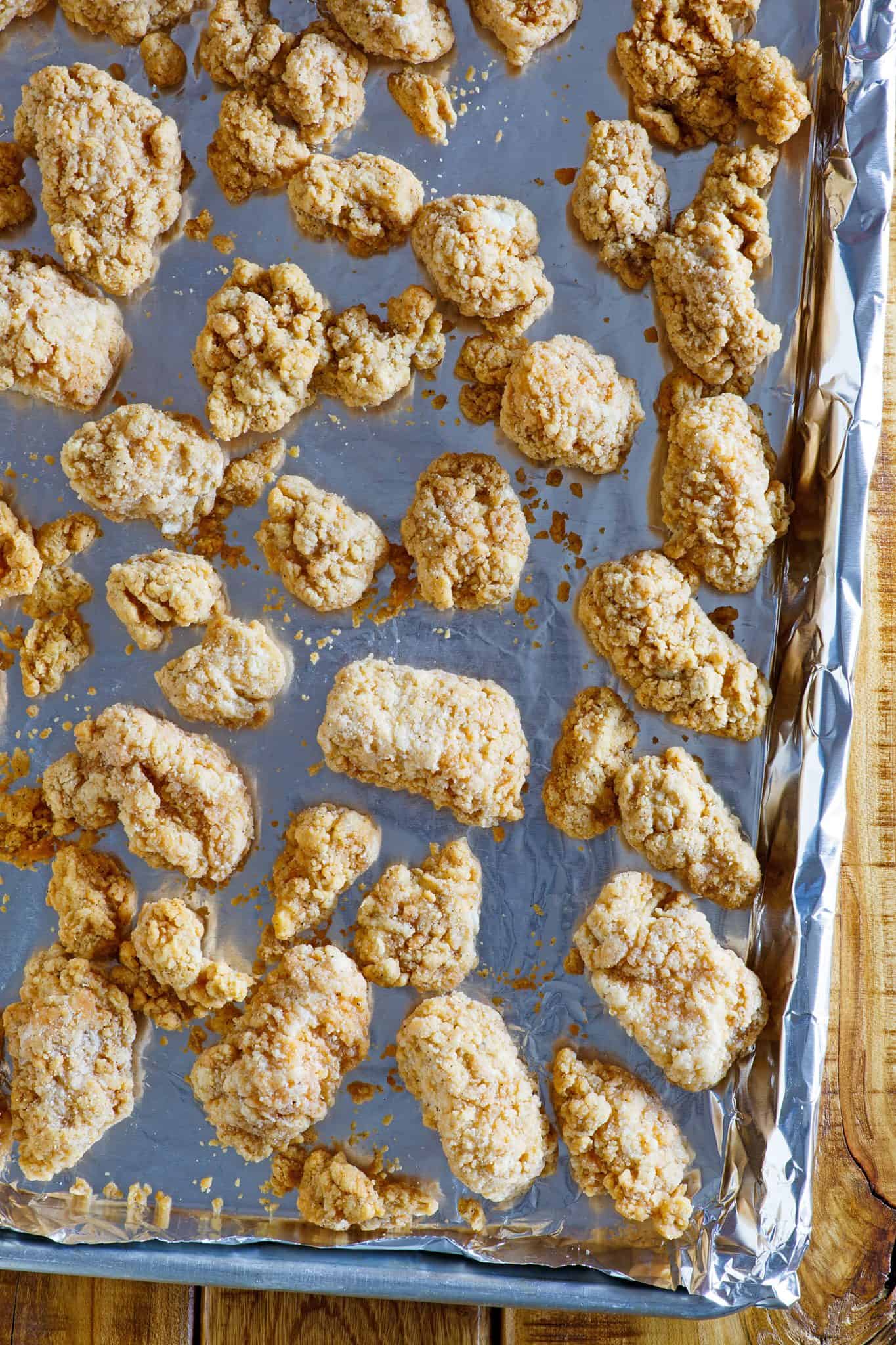 frozen popcorn chicken on baking sheet lined with aluminum foil.