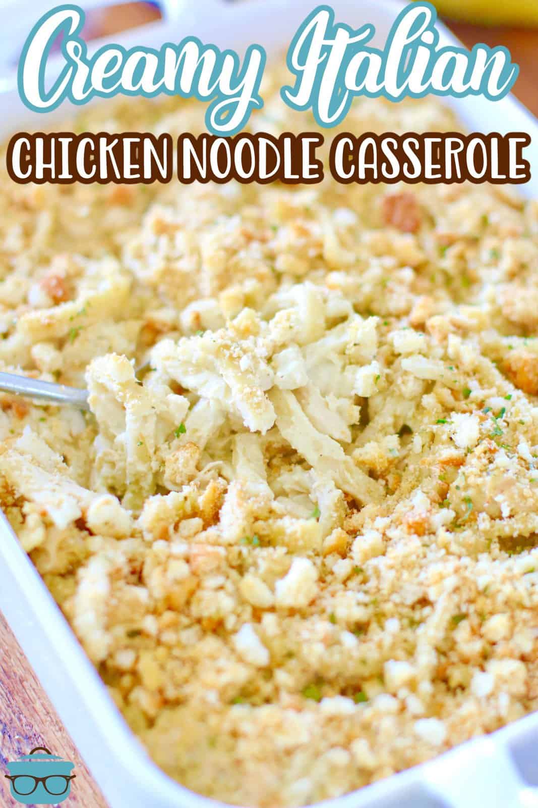 Italian chicken noodle casserole shown in a white baking dish with a spoon inserted.